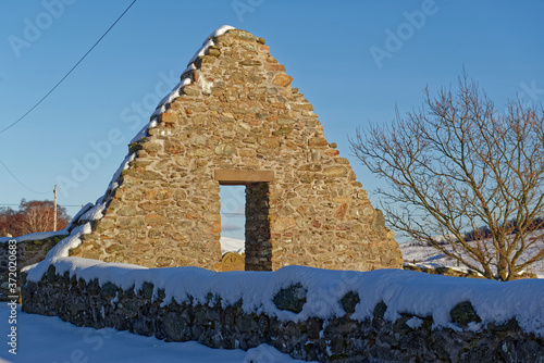 The Snowy ruins of the abandoned Old Glenesk Parish Church at the head of Loch Lee with its triangular shaped East Gable lit up by the evening sun. photo