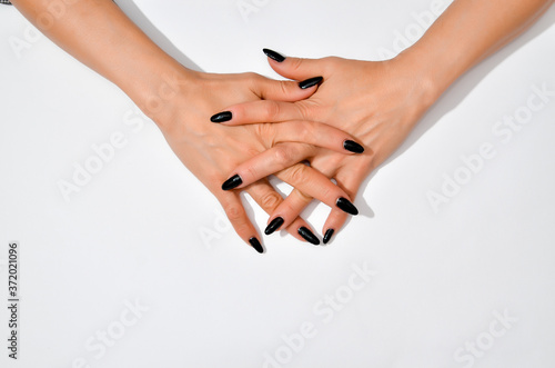 Stylish trendy female black manicure. Beautiful young woman's hands on white background