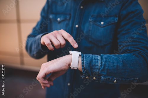 Cropped image on man checking notification on digital smartwatch display planning day with modern organizing app, man's hands with wearable computer wrist watch sending new updates and messages