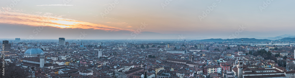 City 's skyline stretching underneath Colle Cidneo at sunset highlights housing space problem, human growth and overpopulation issue. Extensive, spaceless community development - Brescia, Italy