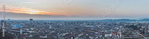 City 's skyline stretching underneath Colle Cidneo at sunset highlights housing space problem, human growth and overpopulation issue. Extensive, spaceless community development - Brescia, Italy photo