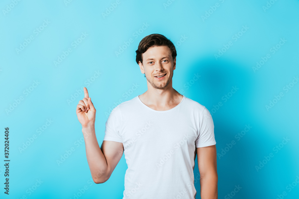 Man in white t-shirt pointing with finger on blue background Man in white t-shirt pointing with finger on blue background