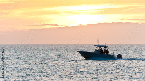 front view, far distance of a power boat cruising toward tropical harbor at sunset on calm waters of the gulf of Mexico