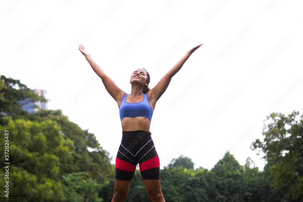 Portrait of fit and sporty young woman doing stretching outside in park