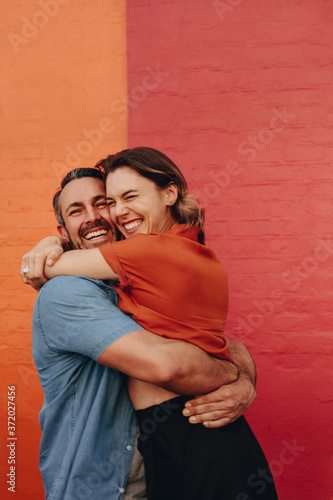 Fényképezés Loving couple embracing against colored wall