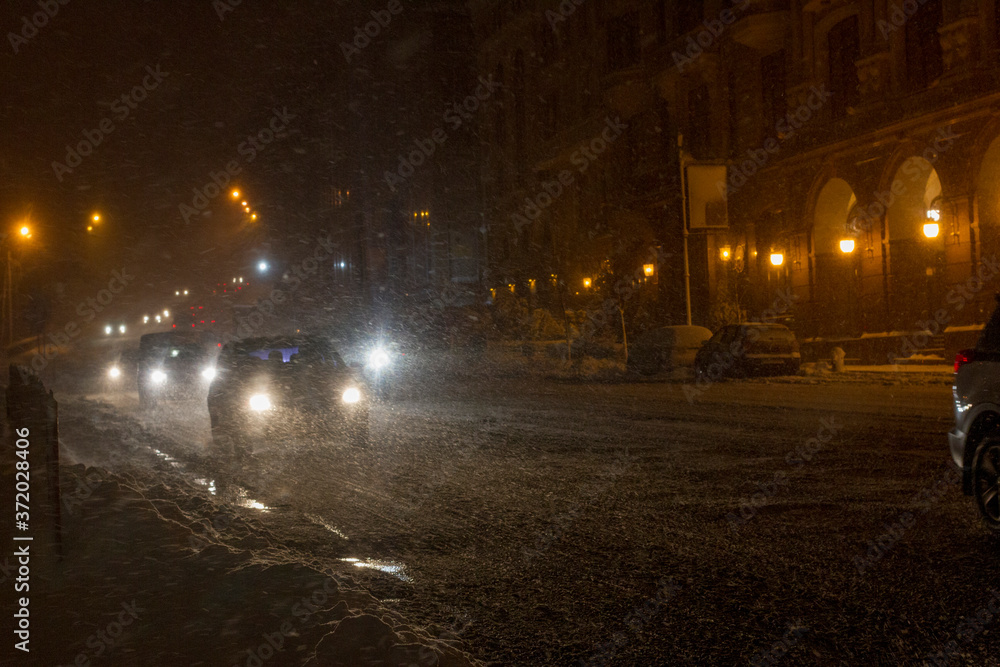 Winter snow storm.Night traffic jam . Car blurred at the street.