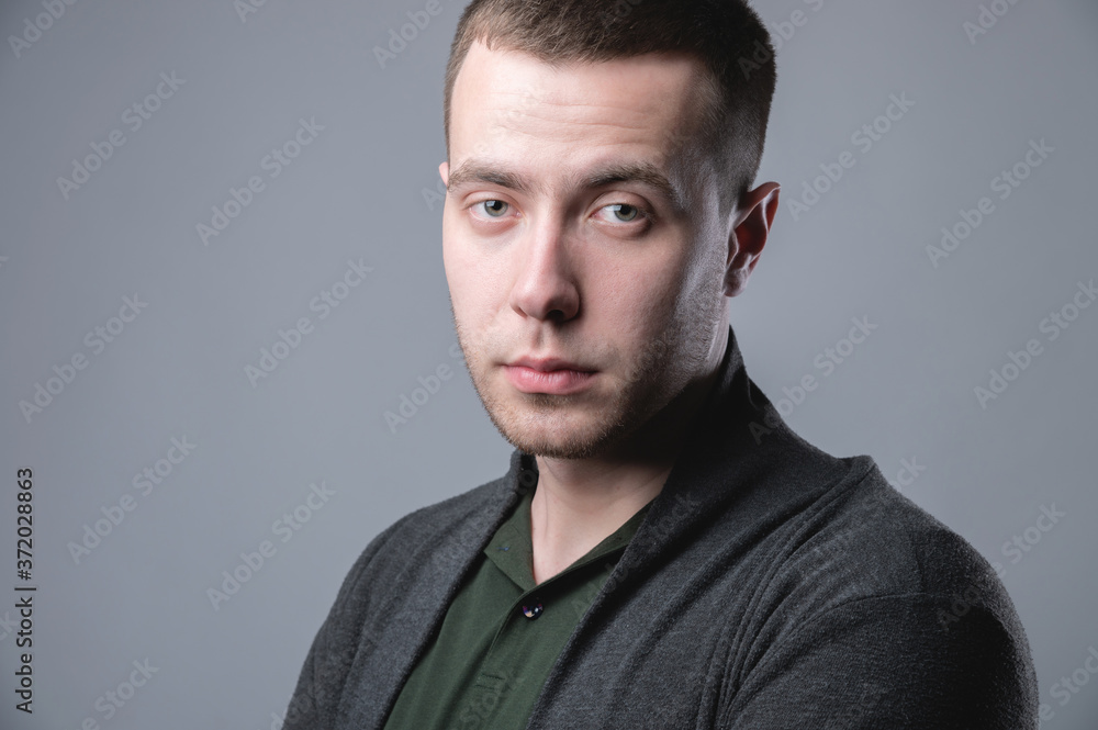 Attractive young man in a pullover positive relaxed view of the portrait studio on a gray background Attractive young man in a pullover positive relaxed view of the portrait studio on a gray background