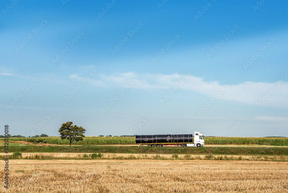 Large truck and trailer with space for text traffic fast on rural road against sky