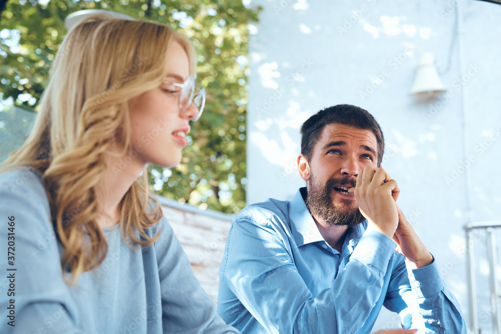 Man and woman communicate in the park outdoors in blue shirts employees friends work Man and woman communicate in the park outdoors in blue shirts employees friends work