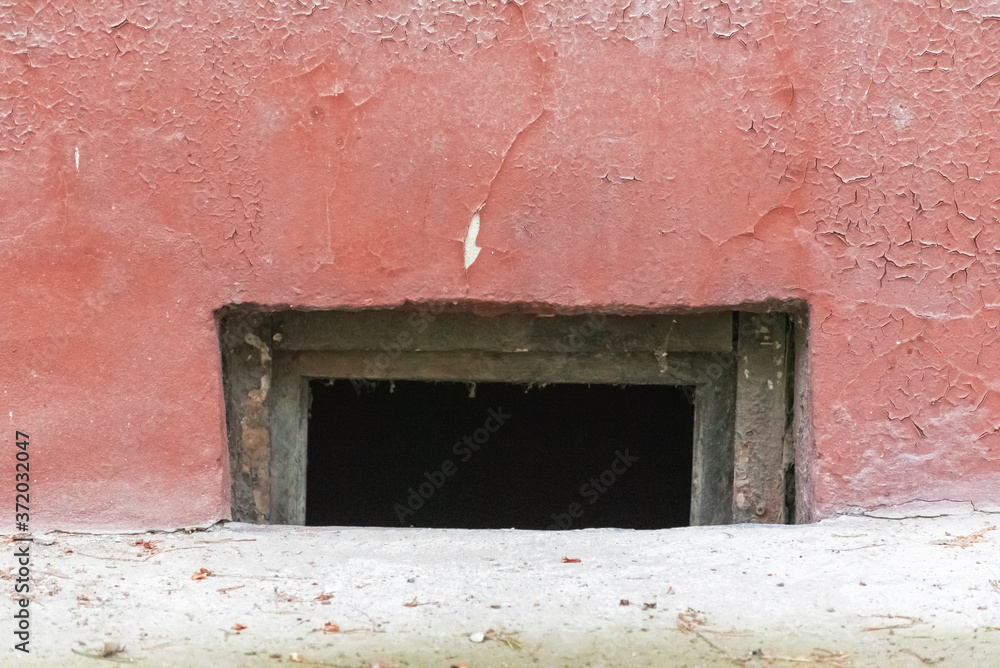 Basement window in an old red painted cracked wall Basement window in an old red painted cracked wall