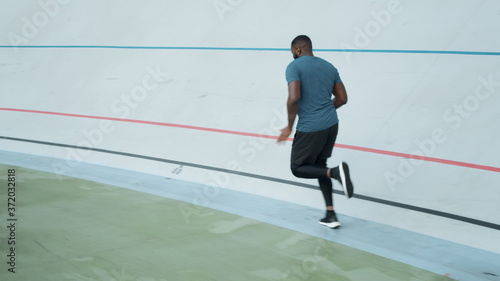 Afro runner training on sports track. Sporty man running on athletics track