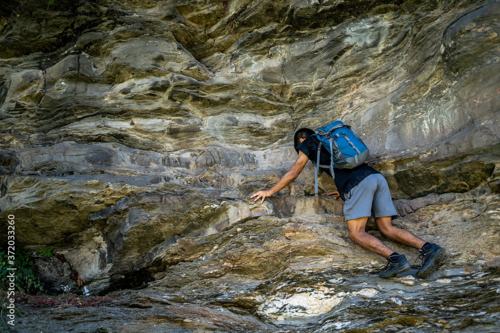 Young boy climbing the rocks wearing a backpack.