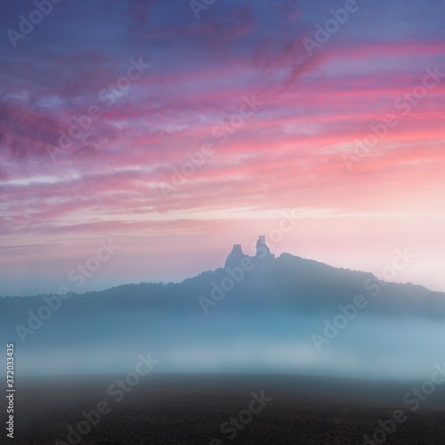 Ruins of old castle Trosky in Bohemian Paradise, Czech Republic. Ruins consist of two devasted towers on the woody hill. Morning landscape with misty atmosphere