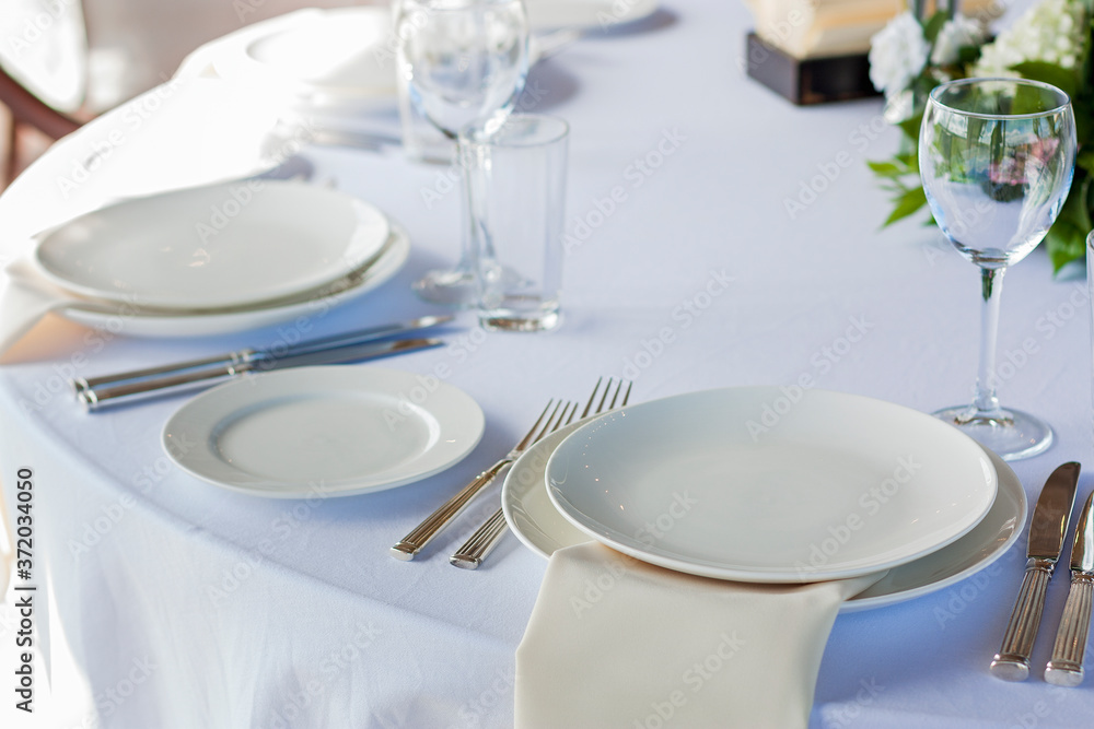 A white plate lies on the table with a white tablecloth on a solemn day