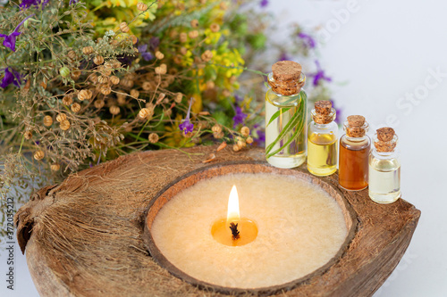 Concept of SPA procedure with herbal essential oils, burning candle and healthy wildflowers