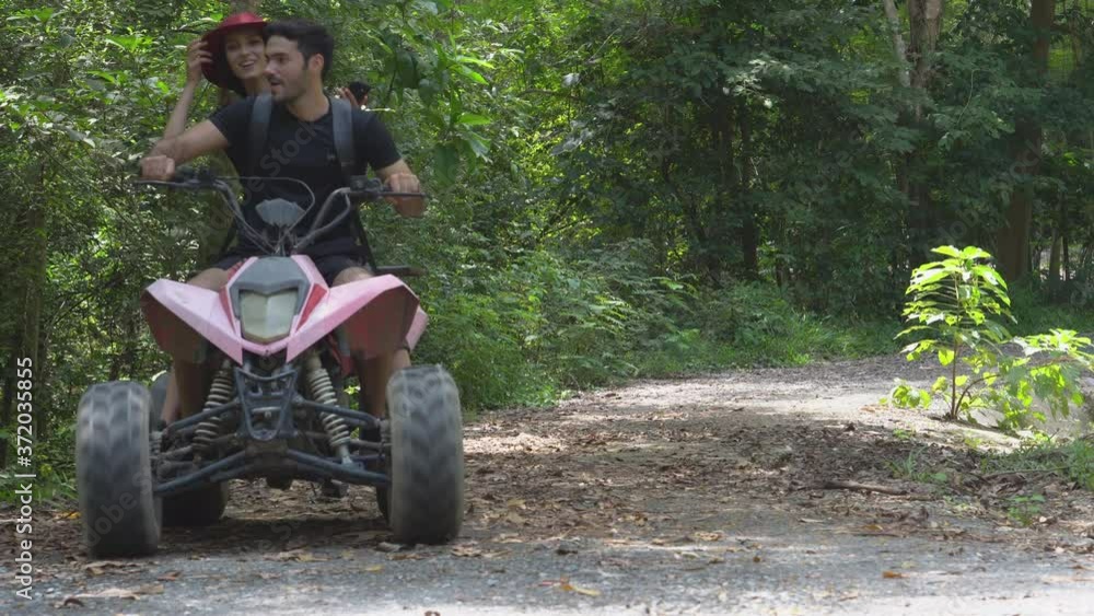 Happy young couple adventure with driving ATV travel trip on road in jungle together, fun and extreme, activity of friend ride vehicle in forest, vacation and holiday with enjoy in summer concept. Happy young couple adventure with driving ATV travel trip on road in jungle together, fun and extreme, activity of friend ride vehicle in forest, vacation and holiday with enjoy in summer concept.
