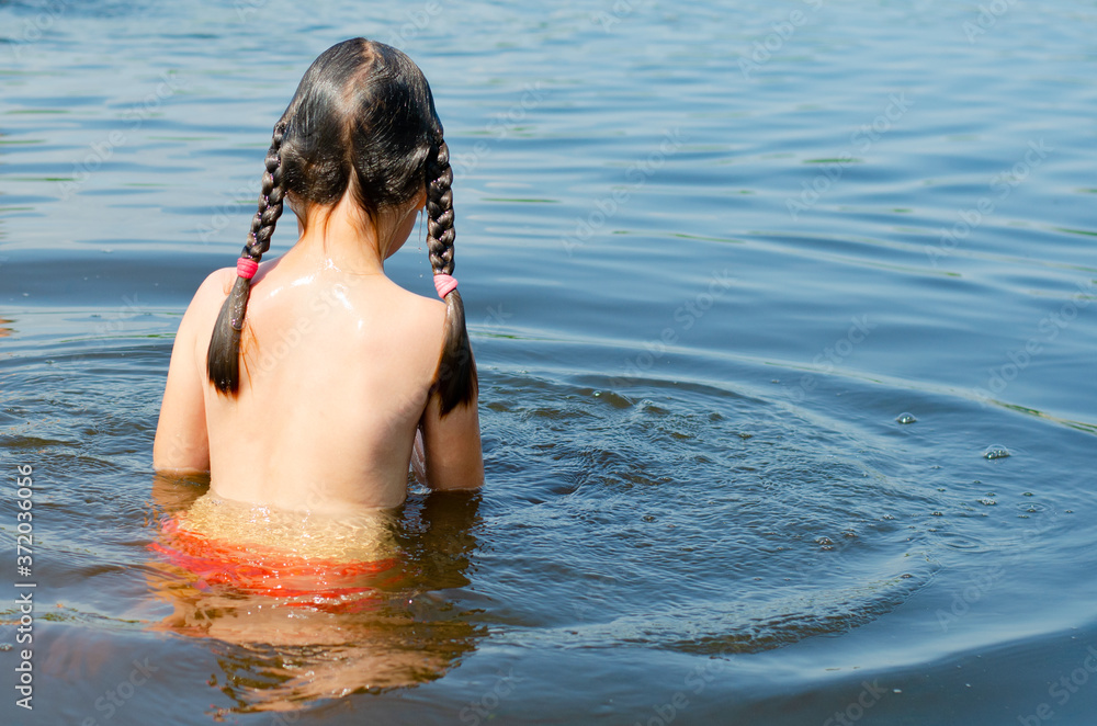 Close up of young beautiful girl in water. Portrait from the back child swimming in the river. Six years caucasian child on vacation. Holiday and summer concept.
