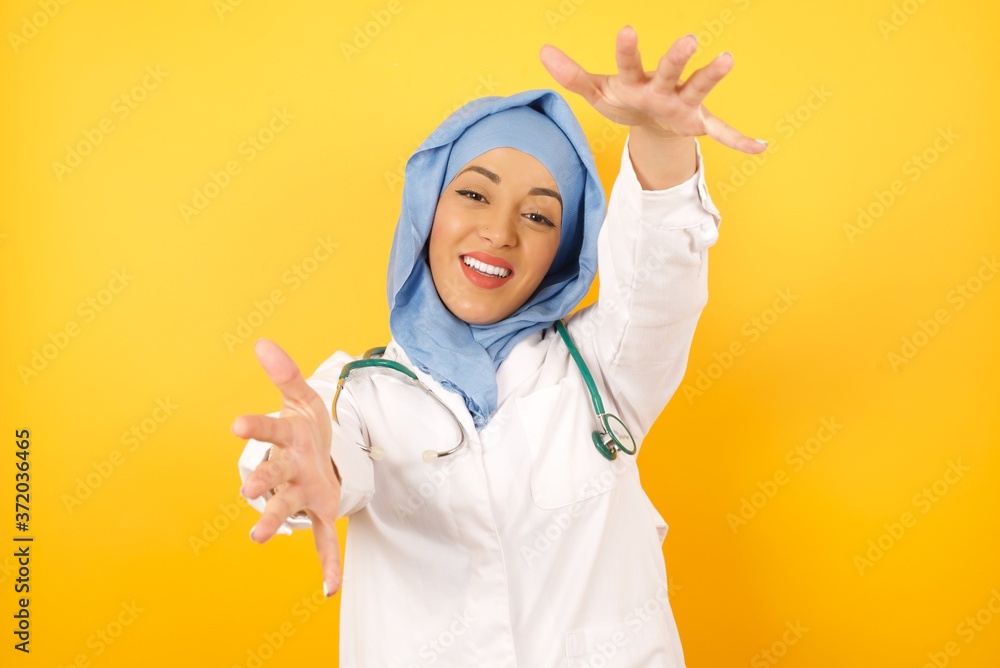 Φωτογραφία Young arab doctor woman wearing medical uniform standing over yellow background  looking at the camera smiling with open arms for hug