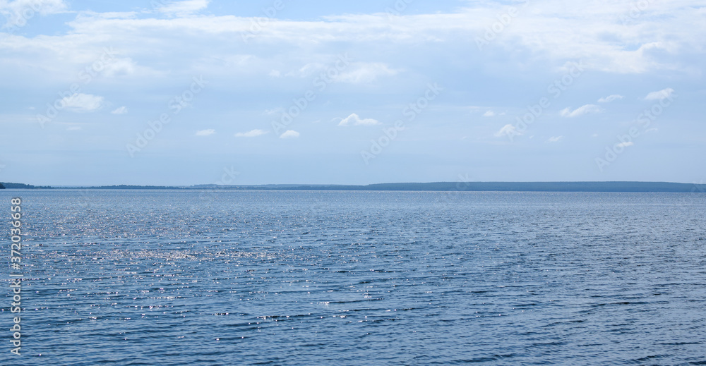 Lake Uvildy, Southern Urals (Chelyabinsk region, Russia). Lake view in summer. Sun glare on the water surface. Selective focus. Lake Uvildy, Southern Urals (Chelyabinsk region, Russia). Lake view in summer. Sun glare on the water surface. Selective focus.