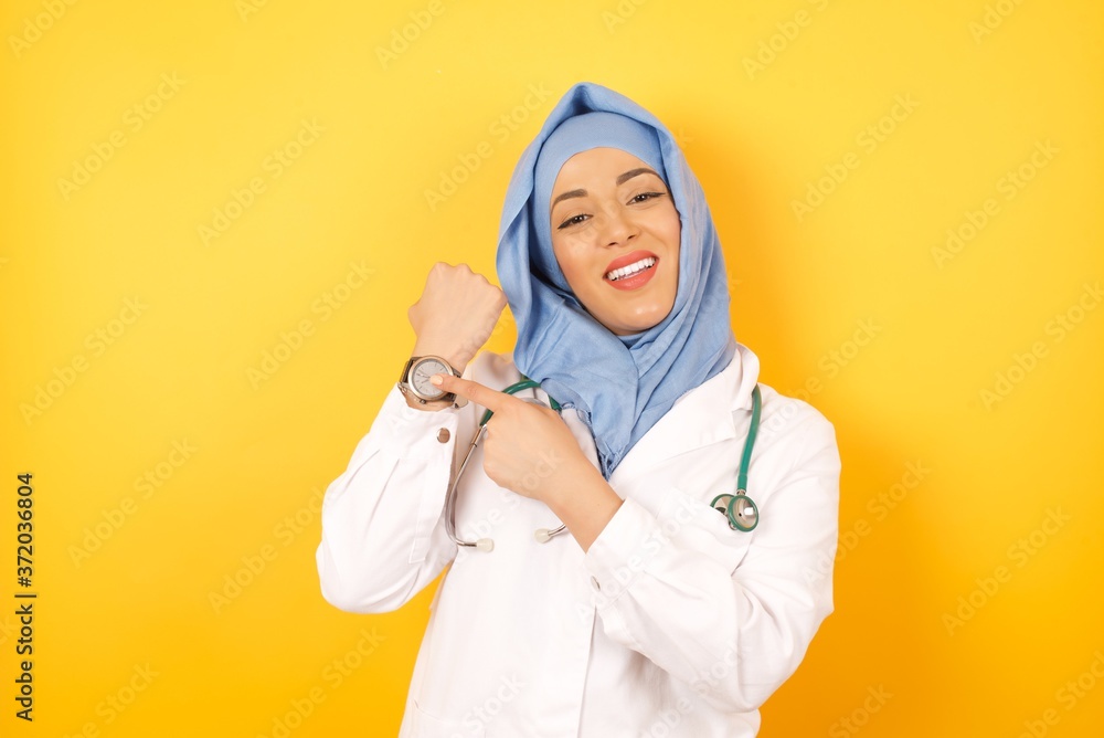 Φωτογραφία Young arab doctor woman wearing medical uniform standing over yellow background