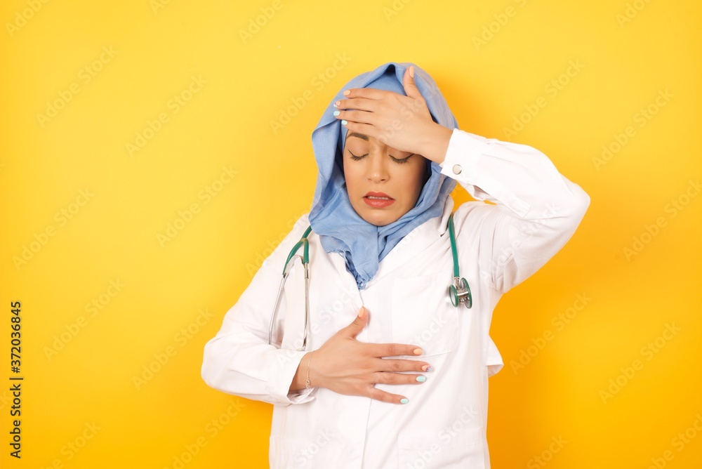 Young arab doctor woman wearing medical uniform standing over yellow background Touching forehead for illness and fever, flu and cold, virus sick. Young arab doctor woman wearing medical uniform standing over yellow background Touching forehead for illness and fever, flu and cold, virus sick.