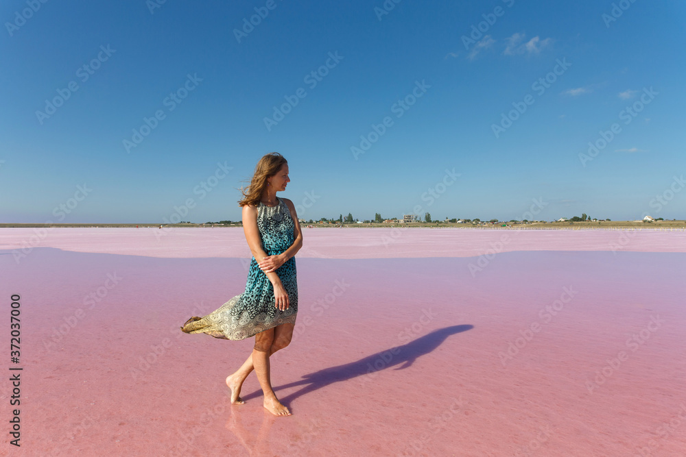 Beautiful young girl on the salt pink lake at Genichesk, Ukraine. portrait a slim woman in bright dress near the pink sea in summer day. travelling Ukraine