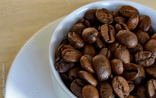 white cup with arabica coffee beans close up