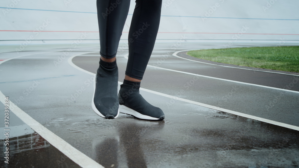 Sporty man warming legs on track. Sportsman feet jogging on spot at stadium Sporty man warming legs on track. Sportsman feet jogging on spot at stadium