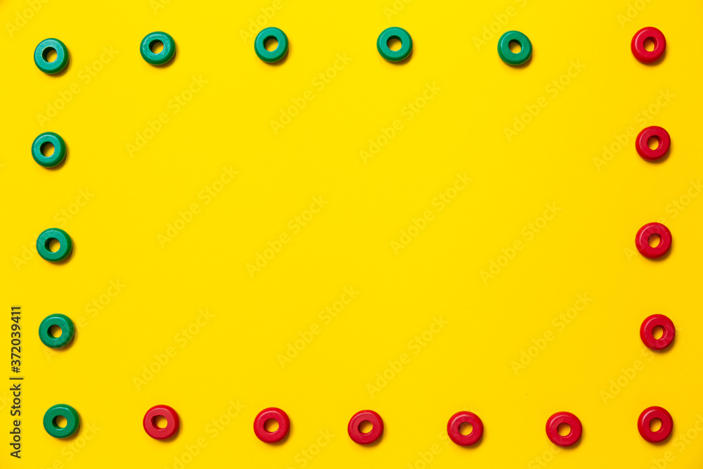 On a yellow background, there are rings of green and red colors of the same size, which form a frame on children's education and development. Backdrop for placing text and other information On a yellow background, there are rings of green and red colors of the same size, which form a frame on children's education and development. Backdrop for placing text and other information