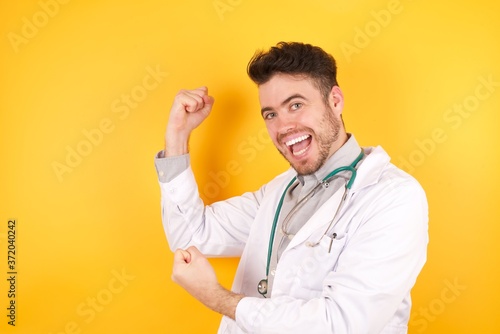 Profile photo of excited Caucasian doctor man wearing medical uniform, raising fists celebrating black friday shopping isolated over white background