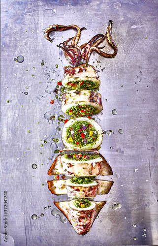 Grilled squid stuffed with couscous and vegetables on a steel table.