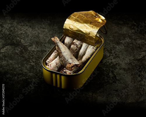 A yellow can of sardines in olive oil over an aged metallic table. Dark environment. photo