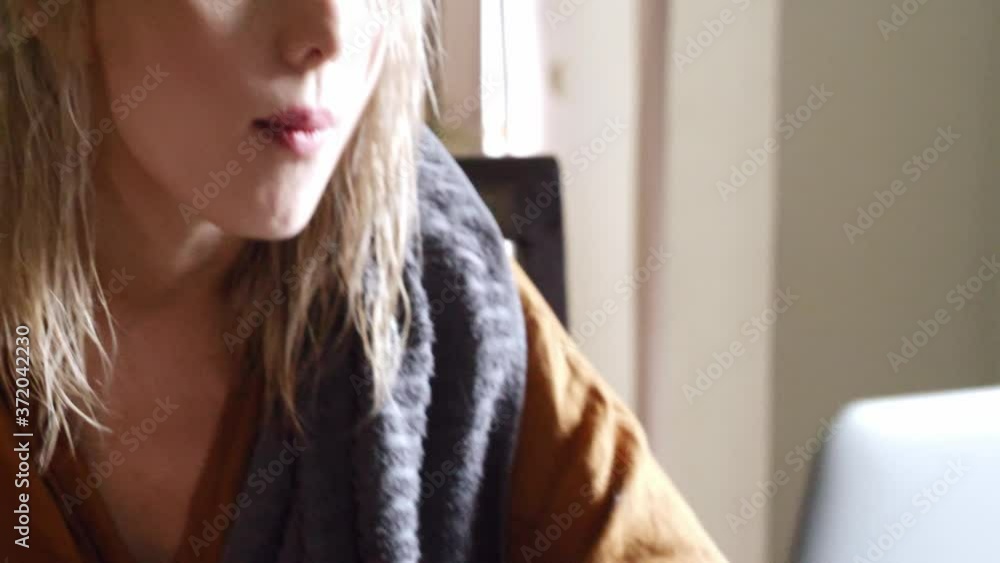 Blonde woman working at home with computer and drinking a coffee Blonde woman working at home with computer and drinking a coffee