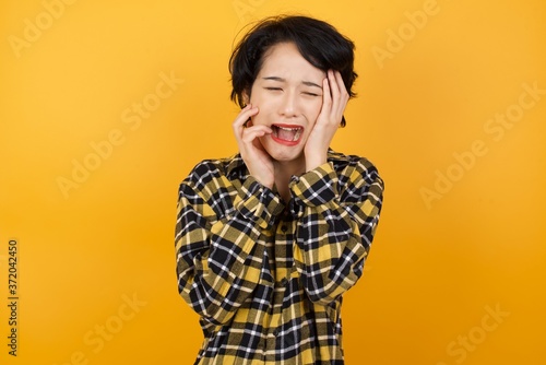 Doleful desperate crying  Young beautiful Asian woman being in depression after quarrel with husband or boyfriend, looks stressfully, frowns face. Pretty female feels lonely and anxious