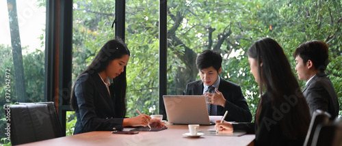 Businesspeople are working while sitting together in the meeting room over a beautiful outdoor as a background.