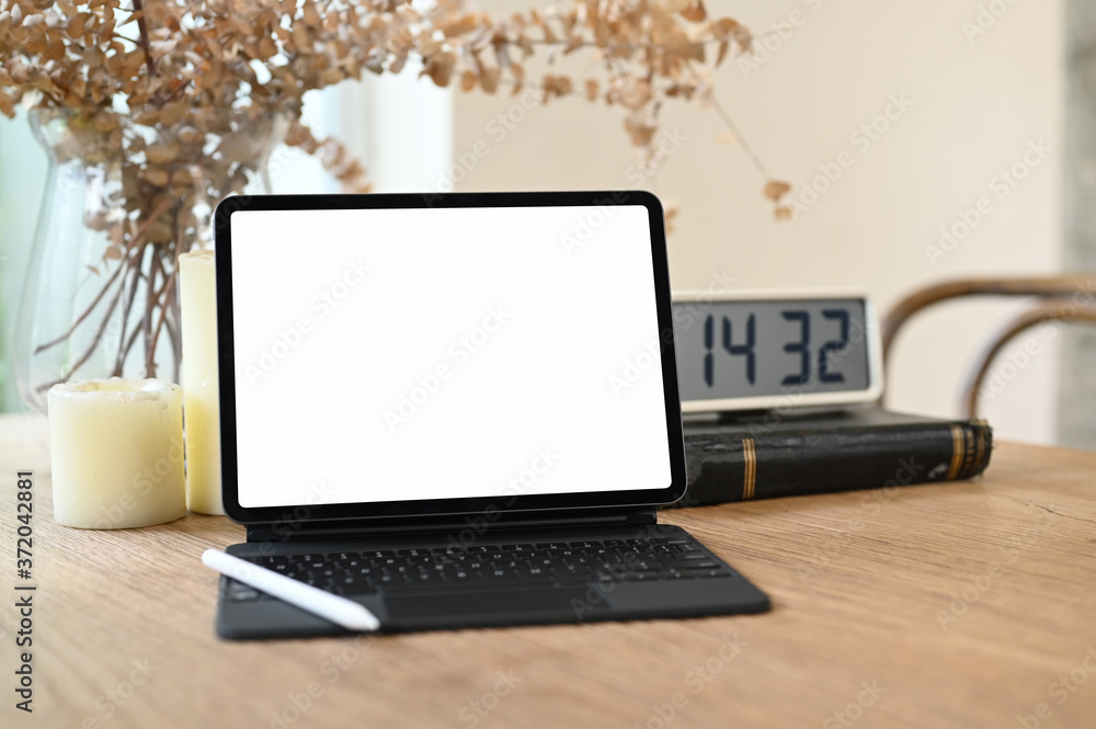 Fototapeta premium Computer tablet with a white blank screen is putting on a wooden table surrounded by various equipment.