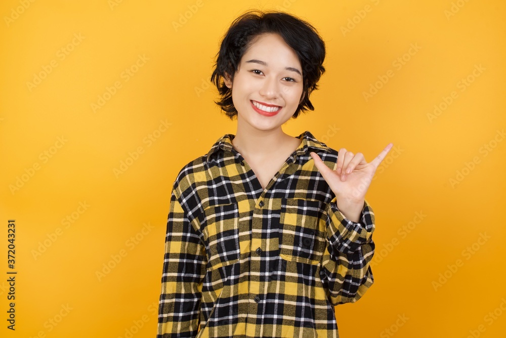 Young asian woman with short hair wearing plaid shirt standing over yellow background showing up number six Liu with fingers gesture in sign Chinese language Young asian woman with short hair wearing plaid shirt standing over yellow background showing up number six Liu with fingers gesture in sign Chinese language