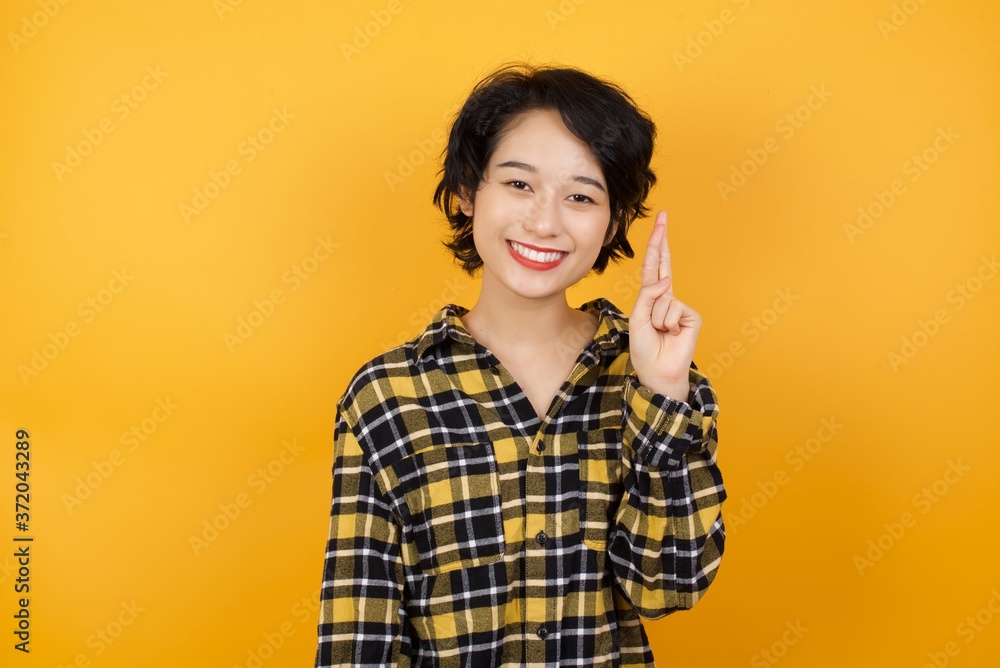 Young asian woman with short hair wearing plaid shirt standing over yellow background pointing up with fingers number ten in Chinese sign language Shi Young asian woman with short hair wearing plaid shirt standing over yellow background pointing up with fingers number ten in Chinese sign language Shi