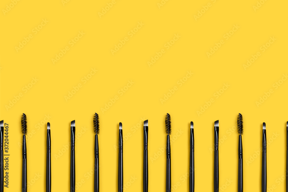 Row of makeup brushes on a yellow background. Beauty composition with copy space. Row of makeup brushes on a yellow background. Beauty composition with copy space.