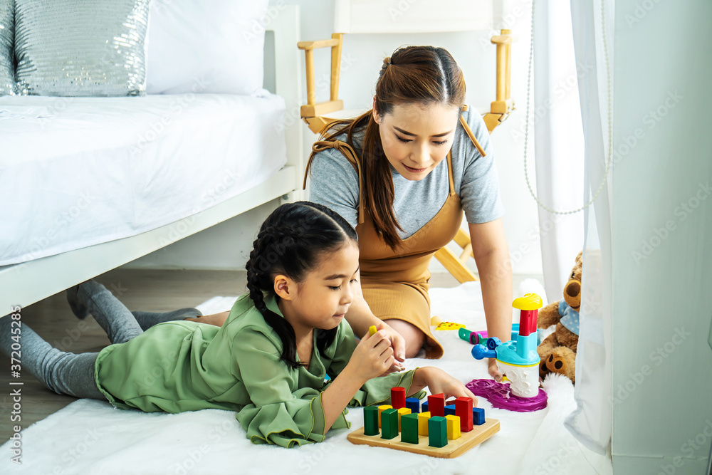 Happy asian mother and asian baby girl playing educational toys on the floor in the bedroom. Home activities for family. Happy asian mother and asian baby girl playing educational toys on the floor in the bedroom. Home activities for family.