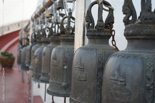 Antique bells decorate lined up by white walls at Wat Saket Temple Bangkok Thailand