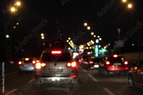 Automobiles with headlights and lights on in the night city. Blurred picture