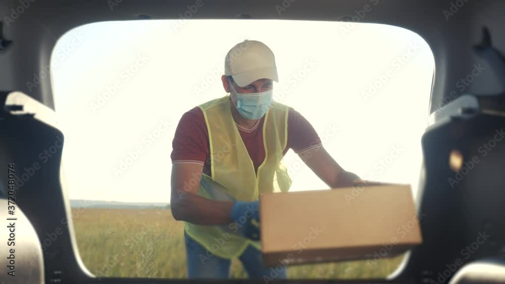 delivery pandemic covid coronavirus vaccine a goods and food product. man volunteer works stacks boxes in a car. parcel delivery concept. courier driver in lifestyle gloves loads boxes during delivery pandemic covid coronavirus vaccine a goods and food product. man volunteer works stacks boxes in a car. parcel delivery concept. courier driver in lifestyle gloves loads boxes during