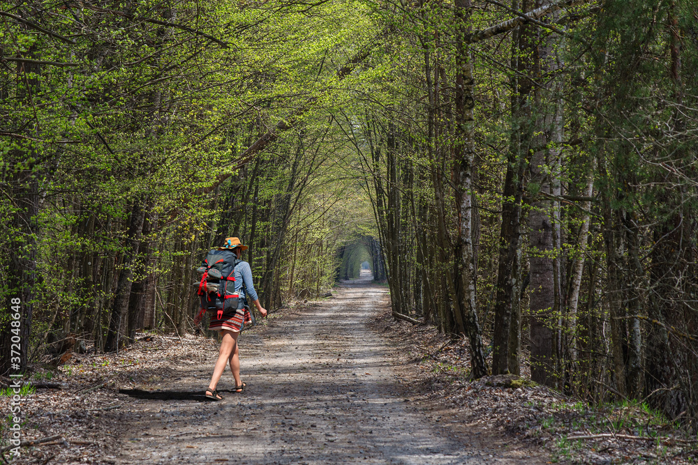 A girl with a backpack in a stylish hat walks through the spring forest. Ukraine A girl with a backpack in a stylish hat walks through the spring forest. Ukraine