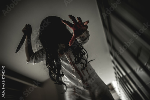 Woman in ghost or zombie on halloween festival at dark place, holding knife and wants to stab you. Horror or halloween festival concept.