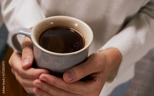 Close-up of a woman's hand holding a cup of hot coffee