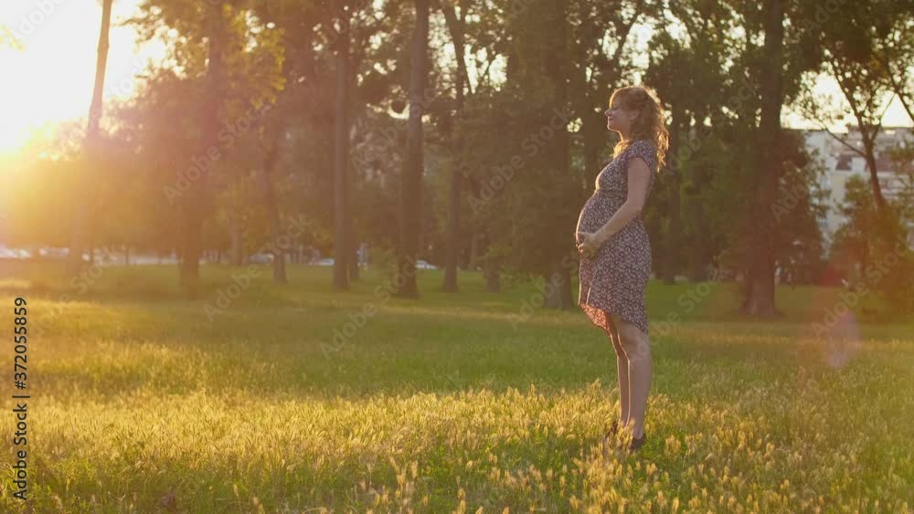 A smiling pregnant woman sun-gazing in the city park A smiling pregnant woman sun-gazing in the city park