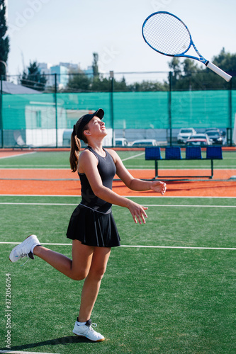 Lighthearted girl training on a tennis court, playing with racket, flipping it © zzzdim