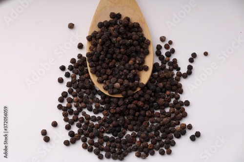 black pepper in wooden spoon isolated on white background.