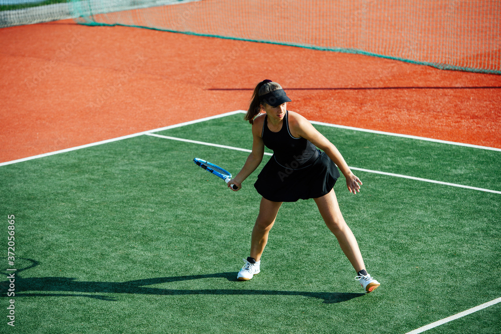 Keen teenage girl playing tennis on a new court, ready to return ball